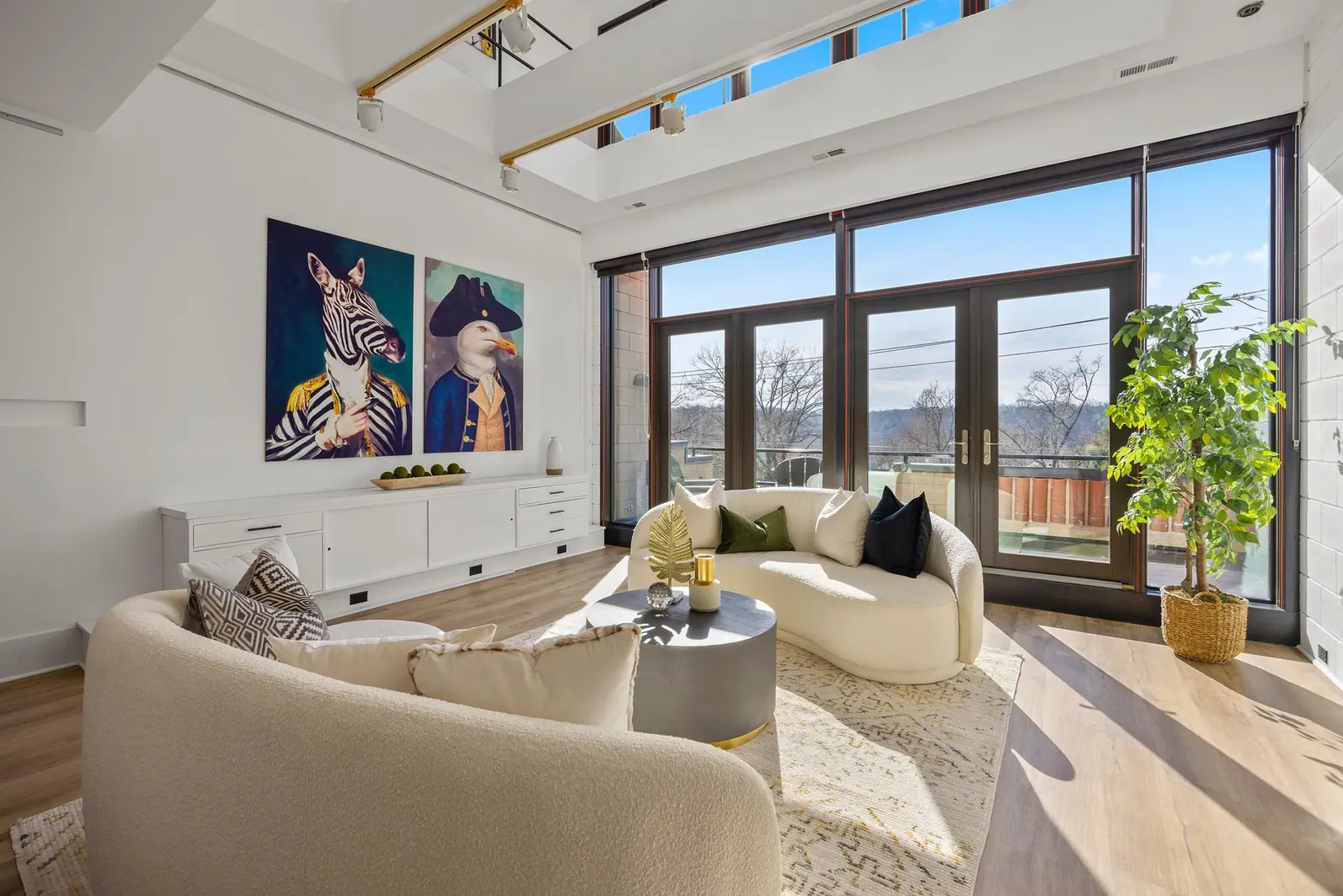 Staged living room with cream sofas, bold artwork and a terrace view