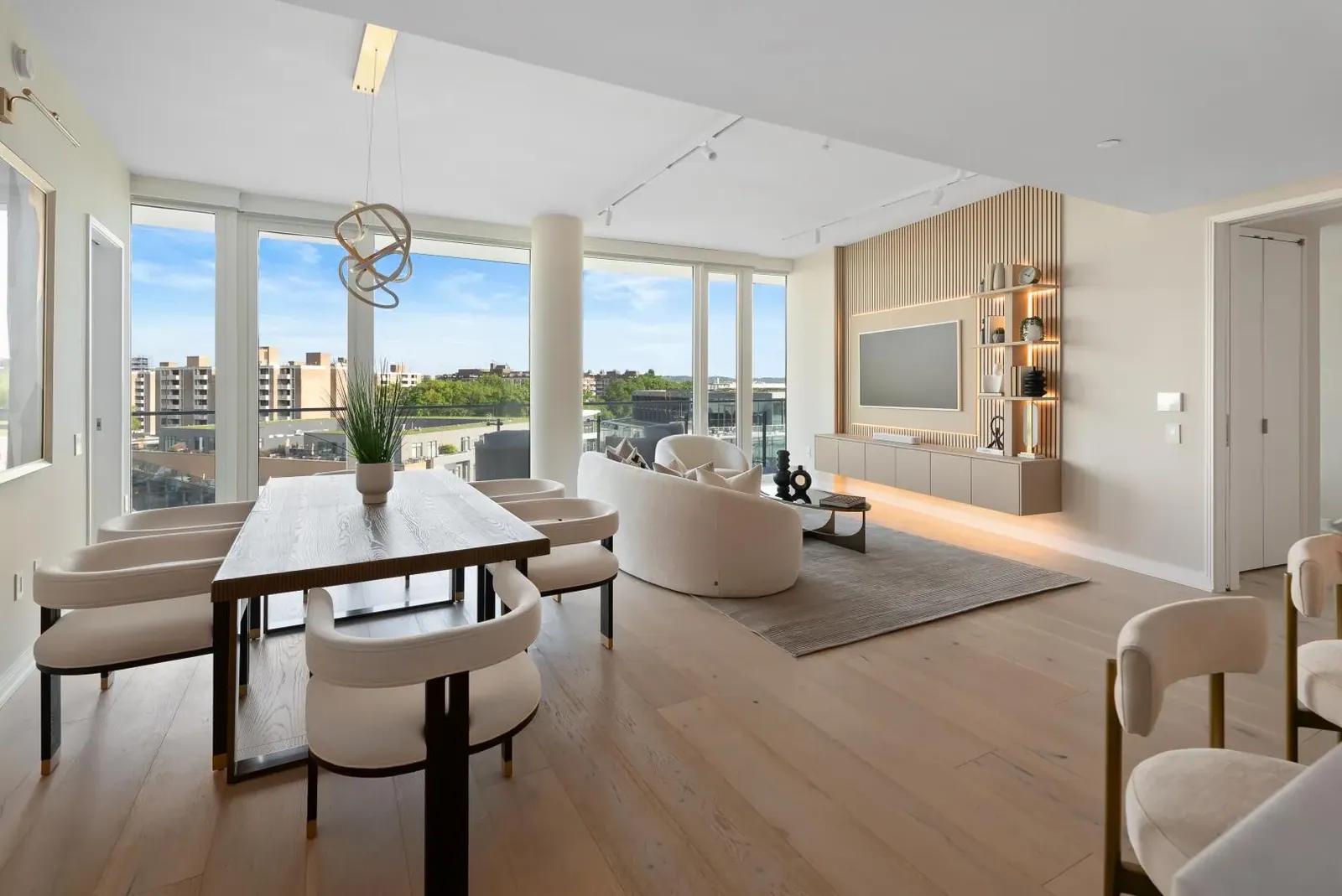 The same room staged with a dining table, curved sofa and an oak media wall
