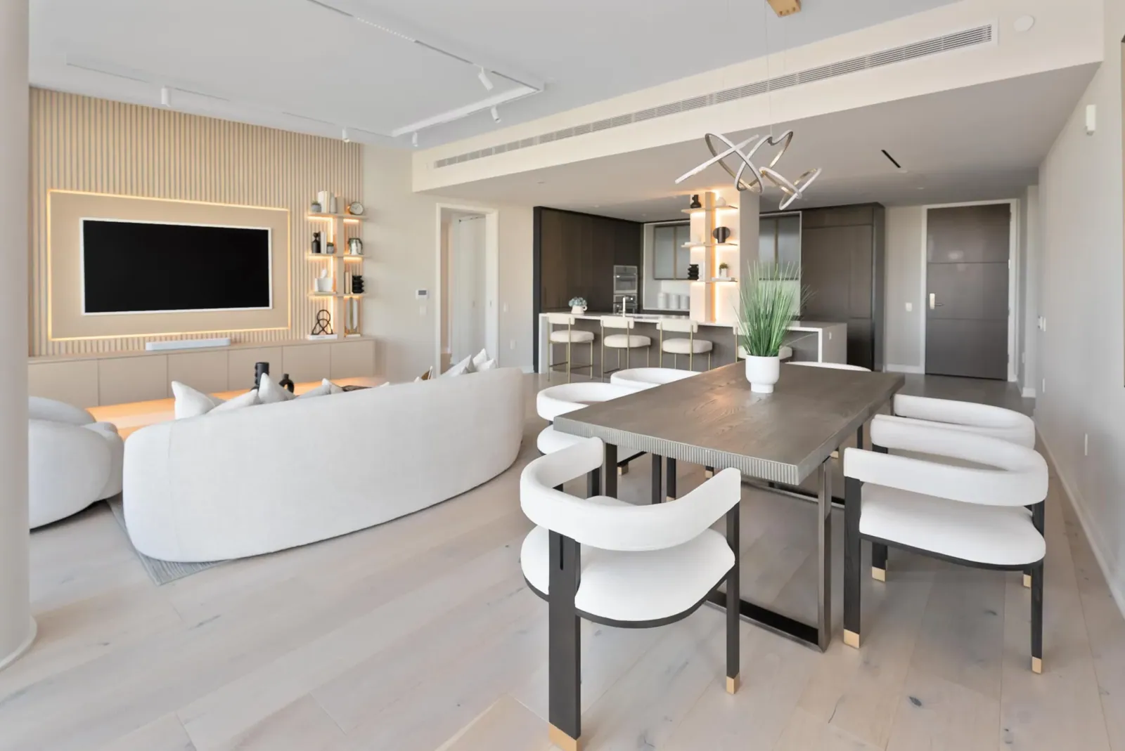Open-plan living and dining room with a white curved sofa and oak media wall