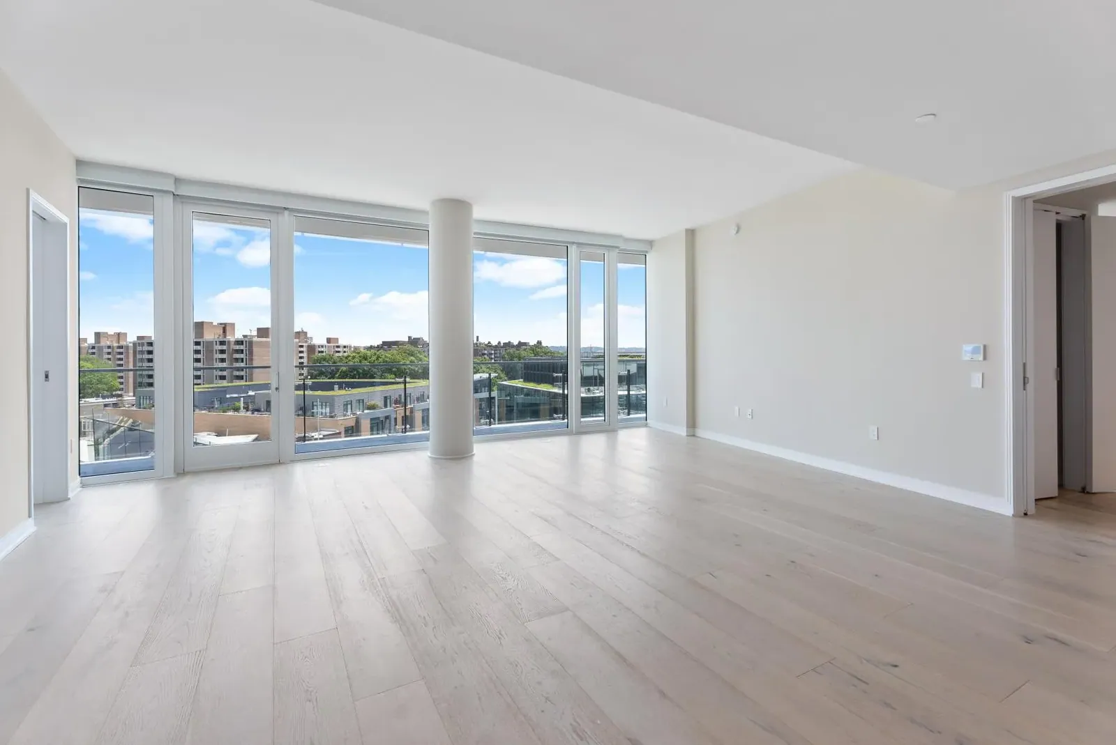 Empty living and dining room with floor-to-ceiling windows, before staging