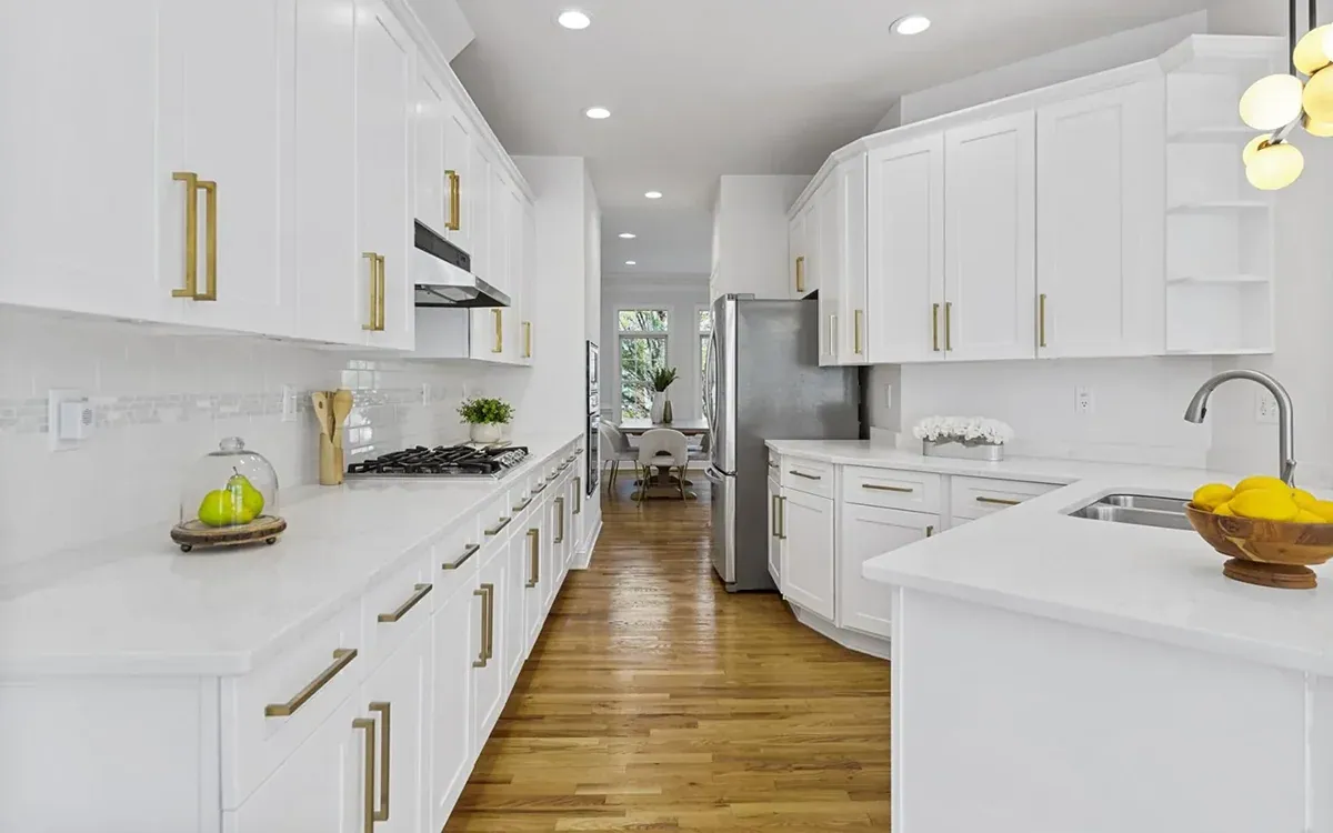 Remodeled kitchen with white cabinetry, quartz countertops and brass hardware