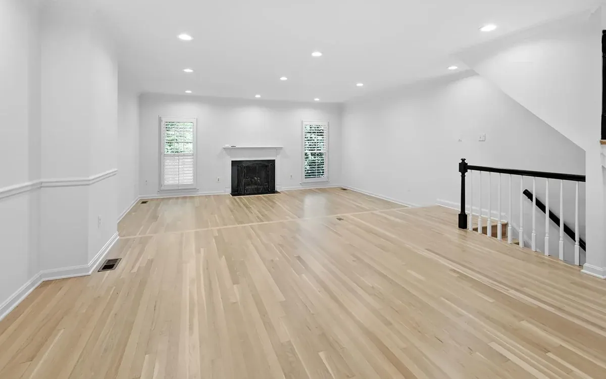 Bright empty living room with new light hardwood floors and fireplace