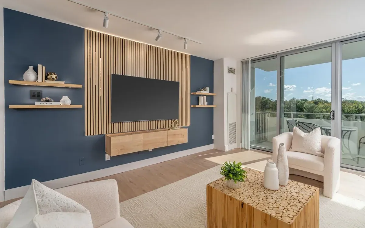 Living room with a navy accent wall, oak-slat media wall and balcony view